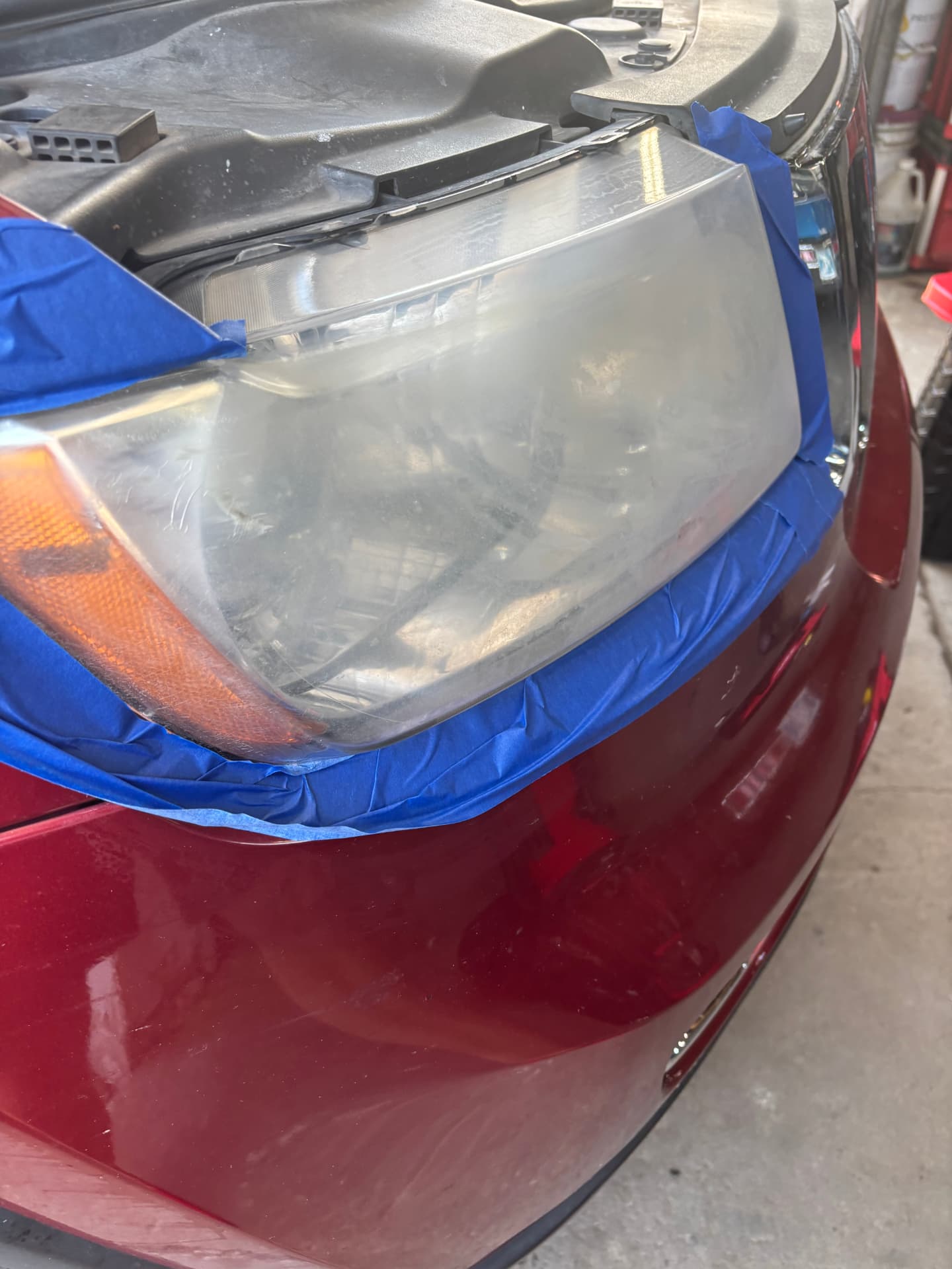 Hazy, oxidized red sedan headlight before restoration
